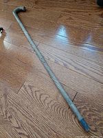 Full length image showing the curved handle and barley twist carved hardwood shaft on wooden floor.