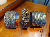 Front view of three vintage metal cuff bracelets showing distinct textures and patterns on each cuff.