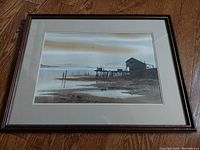Framed watercolour painting showing the full artwork depicting a coastal cannery scene with pier and buildings against a cloudy sky.