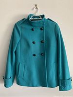 Front view of blue double-breasted jacket with buttons and pockets showing shoulder details.