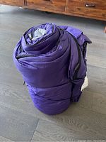 Rolled-up purple Coleman sleeping bag showing its compact storage state.