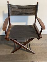 Front view of the director's chair showing wooden frame, black fabric seat and backrest, and armrests.