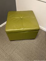 Top view of green faux leather ottoman showing tufted top and overall condition.
