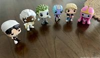 Row of six diverse Funko Pop figures featuring pop culture characters, including Beetlejuice, Storm, Thanos, Ed Sheeran, Princess Bubblegum, and another male character.