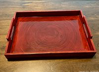 Rectangular wooden serving tray with reddish-brown finish and visible wood grain, measuring 16x12 inches.