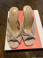 Front view of beige suede heeled sandals with knotted design, placed on a white and orange box, showing the Banana Republic branding on the insole.