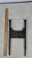 Full view of antique iron boot scraper with ruler for scale showing 18 inch length.