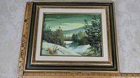 Full image of framed winter landscape oil painting with a ruler for scale showing a size of approximately 14 x 17.5 inches.