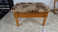 Side view of the foot stool showing floral upholstery and wooden legs.