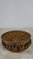 Full basket viewed from front showing woven pattern, braided rim, and decorative colored bands around upper edge.