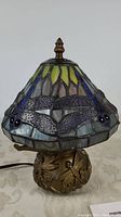Front view of assembled lamp showing stained glass dragonfly shade and bronze-tone metal base