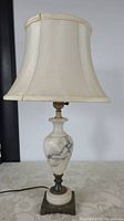 Photo of the vintage table lamp showing the marble body, brass base, and beige fabric shade while lamp is off.