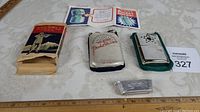 Two vintage pocket warmers displayed alongside original box and printed instructions on fabric-covered table.
