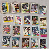 Multiple piles and loose 1980 O-Pee-Chee NHL hockey cards featuring various players and teams such as Canucks, Kings, Oilers, Sabres, Canadiens, Flyers, Bruins, Maple Leafs, Rangers, and more.