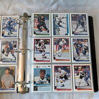 Binder opened to sheet displaying 18 hockey cards featuring various NHL players in action.