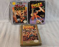 Overview of three NES game boxes and cartridges: Bad Dudes, Rygar, and P.O.W.