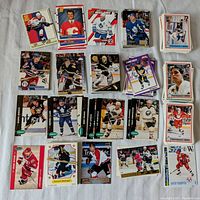 Top view of varied hockey cards laid out showing front designs with players in different team jerseys and action shots predominantly from the 1990s.