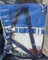 Blue and white beach bag with a belt and star design, packaged in plastic