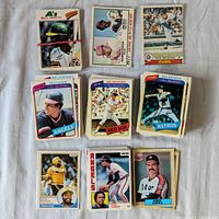Top view of multiple stacks of vintage O-Pee-Chee baseball cards featuring players such as Bill North, Rick Reuschel, Rod Carew, Carl Yastrzemski, Nolan Ryan, Dave Parker, and Dave Lopes, showcasing the front face of the cards with team logos and player photographs.