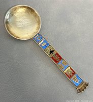 Front view of the sterling silver spoon showing enamel decorated handle with Norwegian motifs and round bowl.