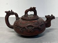 Front view showing dragon handle and spout, detail on dragon relief along body