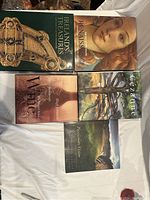 Top view of five assorted coffee table books stacked side by side showing the covers, including 'Ireland's Treasures', 'Renaissance', 'Cézanne', 'Paulomatic Viaton', and 'The World Atlas of Wine'.