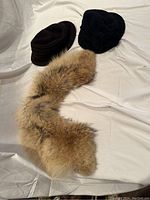 Photo showing two wool hats (brown and black) and a coyote fur collar.