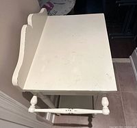 Top angled view of white dry sink table showing flat tabletop and towel bar on one end with turned spindle design.