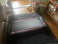 Treadmill laid flat on floor showing running belt and red side stripes