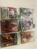 Photo showing six Xbox 360 game cases (FIFA Soccer 12, Call of Duty Modern Warfare 3, Fable III, FIFA Soccer 13, Gears of War 2, Call of Duty Modern Warfare 2) arranged flat on surface.