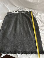 Gray knit skirt laying flat with measuring tape showing length and detail of fringe hem.