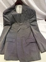 Front view of light grey Hugo Boss men's suit jacket with subtle black checkerboard pattern laid flat on a white backdrop.