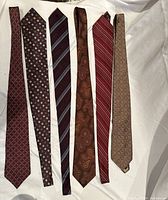 Six silk men's ties laid flat, showing various designs and colors.