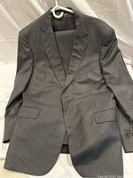 Front view of charcoal grey men's suit jacket with white pinstripes, showing notch lapel and flap pockets.