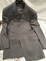 Front view of Paul Smith men's gray pinstripe suit jacket with matching pants on hanger, showing light blue and white stripes.