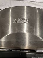 Close-up photo of the branded stainless steel top lid of the Cuisinart Griddler showing 'griddler by Cuisinart' engraving.