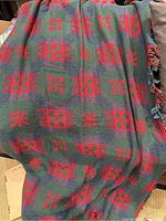 Queen size blanket with dark green and red woven pattern, showing floral and geometric designs and fringed edges.