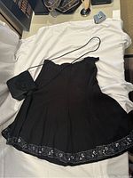 Skirt and bag displayed on white fabric showing full skirt with beaded hem and bag with strap