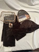 Entire set with hat in packaging, matching scarf laid out, and clear plastic bag containing the set.