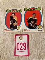 Two 1971-72 OPC hockey cards, Fred Stanfield Center on the left and Don Awrey Defense on the right, with a red oval background and Bruins team name.