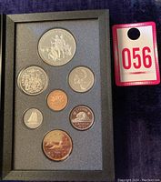 Full view of seven Canadian coins mounted in a gray foam frame with a numbered lot tag beside it.