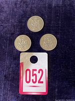 Three 1986 Canadian 50-cent half dollar coins laid out on a dark fabric background with auction tag 052 below.