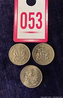 Top view of three Canadian half dollar coins showing the reverse side with the Canadian coat of arms and the dates 1978, 1978, and 1985.
