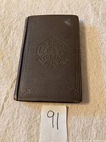 Full front cover of antique mauve hardback book with embossed 'Fireside Library 2 cents' emblem
