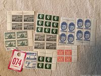 Overview photo showing multiple blocks of Canadian postage stamps from the early 1950s arranged on a light background with a red lot tag labeled "074".