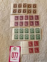 Blocks of mint King George VI Canadian stamps in brown, purple, green, and red colors on beige surface.