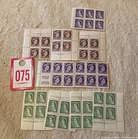 Top view of multiple blocks and strips of early Canadian Queen Elizabeth II mint stamps in different colors and denominations.