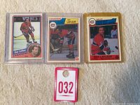 Three encased Guy Lafleur hockey cards grouped on cream cloth background with auction tag.