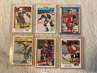 Six hockey rookie cards from various NHL teams including Edmonton Oilers, St. Louis Blues, Calgary Flames, Pittsburgh Penguins, New York Rangers, Philadelphia Flyers in protective cases.