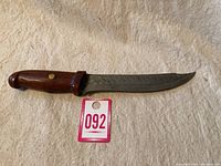 Full view of the KASTO FLEX cutting utensil showing the wooden handle and curved metal blade.